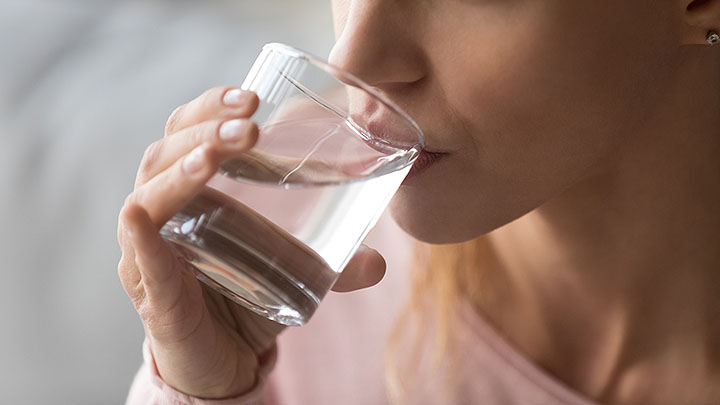 Close-up of a woman drinking water from a glass.